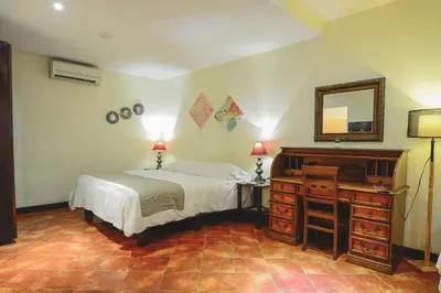 a bedroom with a bed and a dresser and a mirror at Hotel Luisiana in San José