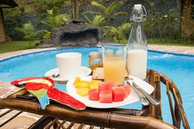 a table with a plate of fruit and a glass of milk at Forest Lodge in Uvita