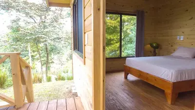 a bedroom with a bed and a large window at Forest Lodge in Uvita