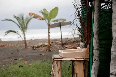 a sink on a wooden stand next to a beach at Miguel Surf Camp in Quepos