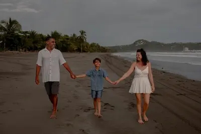 a family walking on the beach holding hands at Miguel Surf Camp in Quepos