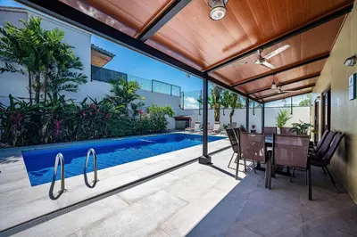 an outdoor patio with a pool and a table and chairs at Casa Gris with private pool near the beach in Jaco in Jacó