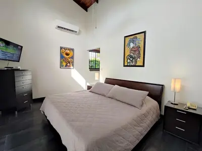 a bedroom with a bed and a flat screen tv at Casa Gris with private pool near the beach in Jaco in Jacó