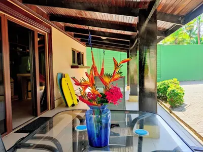 a blue vase with flowers on a glass table at Casa Mandolina on the beach in Jaco in Jacó