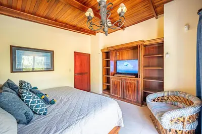 a bedroom with a bed and a tv and a couch at Casa Mandolina on the beach in Jaco in Jacó