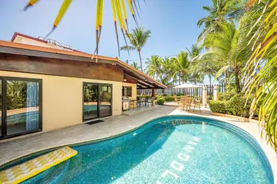 a swimming pool in front of a house with palm trees at Casa Mandolina on the beach in Jaco in Jacó