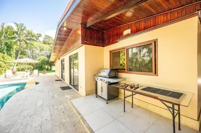 an outdoor kitchen with a grill next to a swimming pool at Casa Mandolina on the beach in Jaco in Jacó