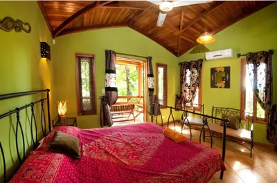 a bedroom with a large bed with a red comforter at Quinta Teca with two pools near Playa Hermosa beach in Playa Hermosa