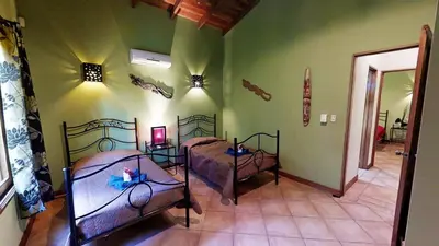 two beds in a room with green walls at Quinta Teca with two pools near Playa Hermosa beach in Playa Hermosa