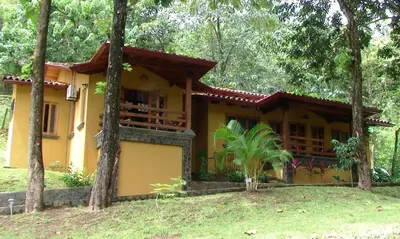 a yellow house with trees in front of it at Quinta Teca with two pools near Playa Hermosa beach in Playa Hermosa