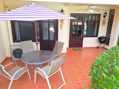 a table and chairs with an umbrella on a patio at Rio Copey 2 townhouse near the beach in Jaco in Jacó