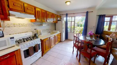 a kitchen with a stove and a table in a room at Rio Copey 2 townhouse near the beach in Jaco in Jacó