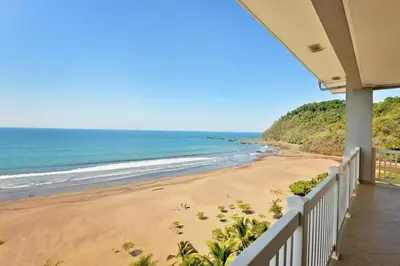 a view of the beach from the balcony of a house at The Palms Jaco 1001 penthouse on the beach in Jacó