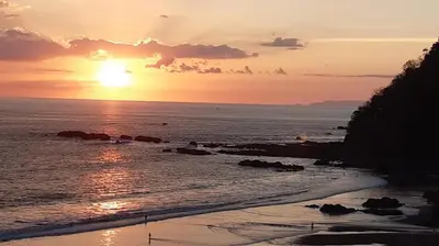 a sunset over the ocean with the sun setting at The Palms Jaco 1001 penthouse on the beach in Jacó