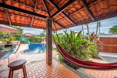 a hammock in a patio with a swimming pool at Villa Jaco Sol 4 bdr resort pool near the beach in Jacó