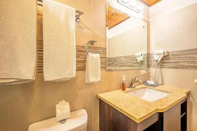 a bathroom with a sink and a toilet and a mirror at Villa Jaco Sol 4 bdr resort pool near the beach in Jacó