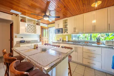 a kitchen with a table and a ceiling fan at Villa Jaco Sol 4 bdr resort pool near the beach in Jacó