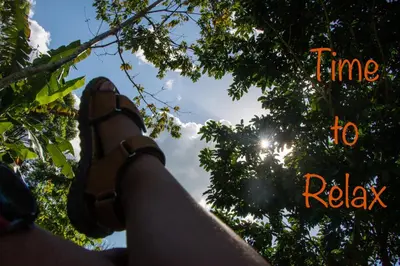 a person with their feet up in a tree with the sun in the background at Eco Guest House - Sarapiquí 1 in Sarapiquí