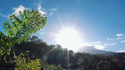 a sun is shining in the sky above trees at Origins Lodge in Bijagua