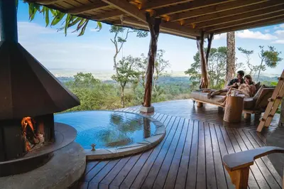 people sitting on a deck with a fireplace on a house at Origins Lodge in Bijagua