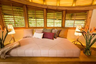 a bedroom with a large white bed with windows at Origins Lodge in Bijagua
