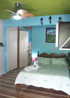 a bedroom with a bed with blue walls and a ceiling at Cabinas Cascada Rio Celeste in Bijagua