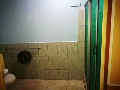 a bathroom with a toilet and a rainbow shower curtain at Hospedaje Las Orquídeas in Venecia
