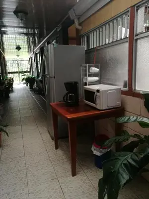 a microwave on a table next to a refrigerator at Hospedaje Las Orquídeas in Venecia