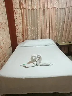 a bed with a pair of slippers on it at Hospedaje Las Orquídeas in Venecia
