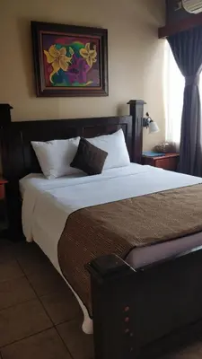 a bedroom with a large bed with white sheets at Hotel Las Colinas in Fortuna