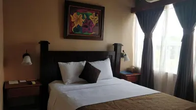 a bedroom with a bed with white sheets and a window at Hotel Las Colinas in Fortuna