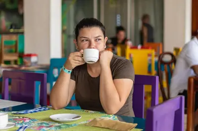 a man sitting at a table drinking a cup of coffee at Hotel Las Colinas in Fortuna