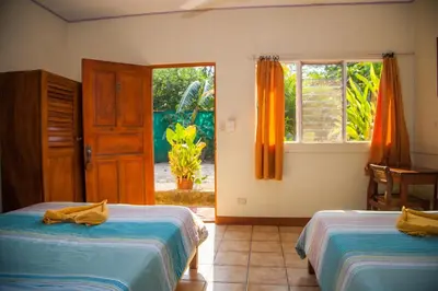a bedroom with two beds and a window and a door at Hotel Brasilito in Brasilito