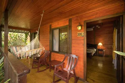 a porch of a wooden cabin with chairs and a hammock at Blue River Resort & Hot Springs in Liberia