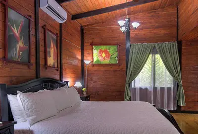 a bedroom with a white bed with wooden walls and a window at Blue River Resort & Hot Springs in Liberia