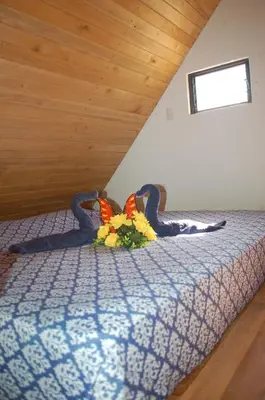a bed with a blue comforter with flowers on it at Casa bungalow Ital-Tico in Paraíso