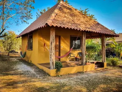 a small yellow house with a thatched roof at Casa bungalow Ital-Tico in Paraíso