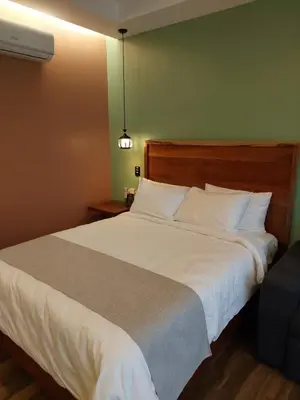 a bedroom with a large white bed and a chair at Hotel Mi Linda Tierra in Quesada
