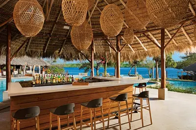a bar in a resort with a view of the ocean at Secrets Papagayo All Inclusive - Adults Only in Papagayo, Guanacaste