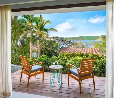 a patio with two chairs and a table on a deck at Secrets Papagayo All Inclusive - Adults Only in Papagayo, Guanacaste