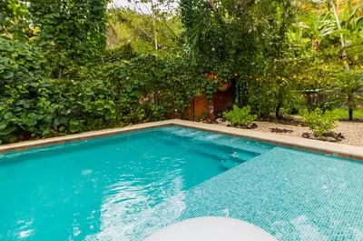 a swimming pool in a yard with trees at Villas Wanderlust in Puntarenas