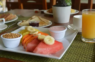 a plate of fruit and vegetables on a table with juice at Arenal Roca Suites in Fortuna