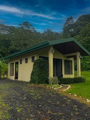 a small yellow house with a green roof at Arenal Roca Suites in Fortuna