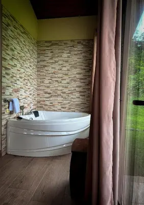 a white tub in a bathroom with a brick wall at Arenal Roca Suites in Fortuna