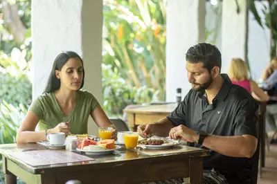 a man and woman sitting at a table eating food at Hotel Aeropuerto in Alajuela City