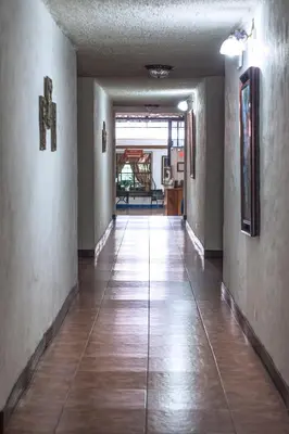 an empty hallway with wood floors and a cross on the wall at Hotel Aeropuerto in Alajuela City
