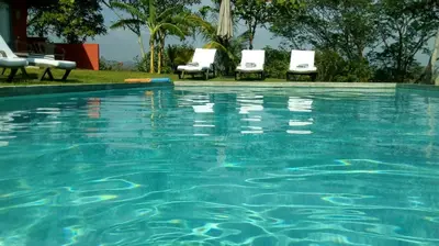 a swimming pool with two chairs and a swimming pool at El nido rojo in Sámara