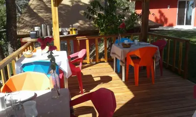 a wooden deck with tables and chairs on it at El nido rojo in Sámara