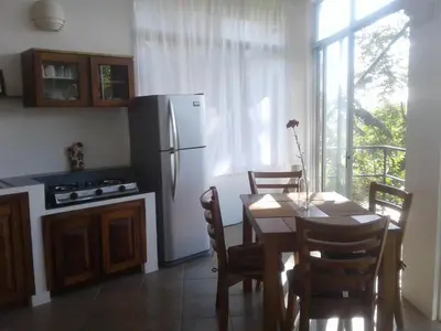 a kitchen with a table and a white refrigerator at El nido rojo in Sámara
