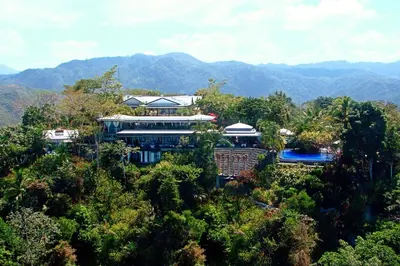 a large building in the middle of a forest at Hotel Villa Caletas in Jacó